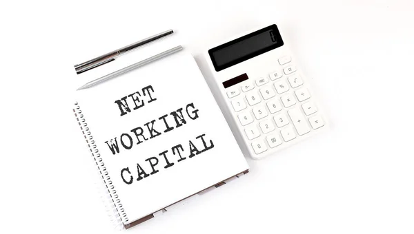 Notepad with text NET WORKING CAPITAL with calculator and pen. White background.