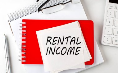 Not defterindeki etiket üzerinde kalem ve hesap makinesiyle RENTAL Gelir sözcüğü