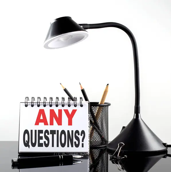 黒の背景にペンとテーブルランプ付きノートブック上の任意の質問テキスト — ストック写真