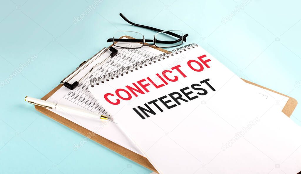 CONFLICT OF INTEREST text on notepad on clipboard with chart on a blue background, concept closeup. Business and finance concept