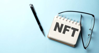 Mavi arkaplanda not defterine yazılmış NFT metni