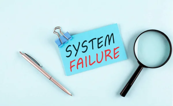 SYSTEM FAILURE text written on sticky with magnifier and pen, business concept