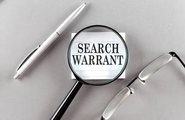 SEARCH WARRANT text written on a sticky with pencil and glasses text written on sticky with pencil and glasses