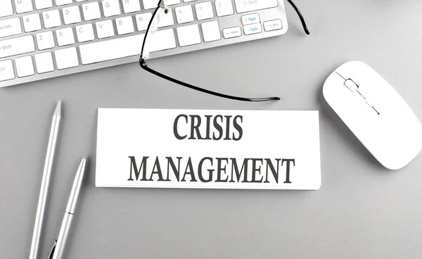 CRISIS MANAGEMENT text on a paper with keyboard on grey background