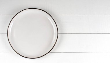 Tahta bir masanın üzerinde boş, beyaz bir tabak. Boşluğu kopyala