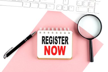 İş konsepti. Pembe kağıda, büyüteçle, klavyeyle ve kalemle beyaz arkaplanlı bir not defteri.