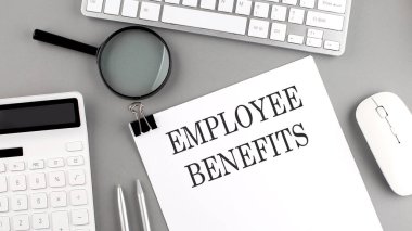 EMPLOYEE BENEFITS Gri arka planda ofis araçları ve klavye ile kağıt üzerine yazılmış