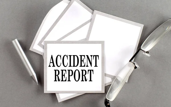 ACCIDENT REPORT text written on sticky with pencil and glasses