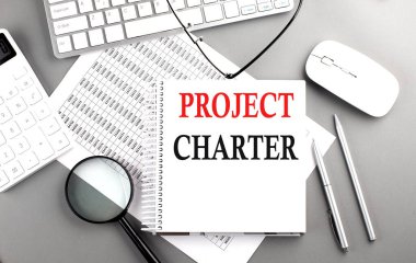 PROJECT CHARTER text on notepad on chart with keyboard and calculator on a grey background clipart