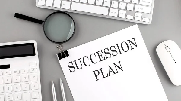 SUCCESSION PLAN written on a paper with office tools and keyboard on the grey background