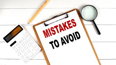 Hesap makinesi, büyüteç ve beyaz ahşap zemin üzerindeki kalemle panodaki sözcükleri kaldırma hatası