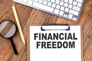 Kağıt pano üzerinde ahşap bir zemin üzerinde büyüteç ve klavye ile FRANSIAL FREEDOM metin