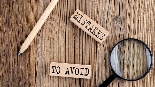 MISTAKES TO AVOID words on a wooden building blocks on the wooden background