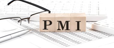 PMI - 'Satın Alma Yöneticileri İndeksi' klavye, hesap makinesi, çizelge, gözlük ile tahtadan bir küp üzerine yazıldı. İş konsepti