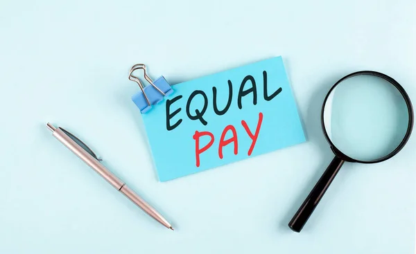 EQUAL PAY text written on sticky with magnifier and pen, business concept