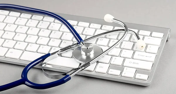 Stethoscope on a computer keyboard on the grey backgroun