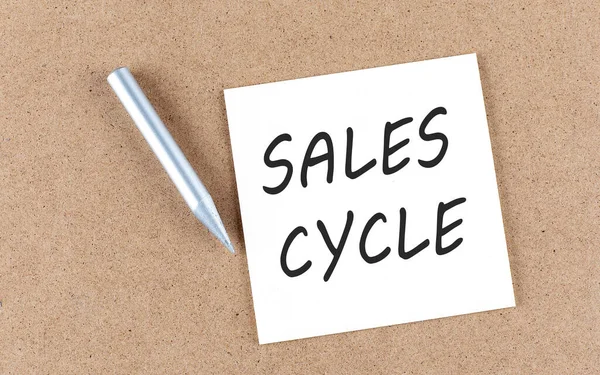 SALES CYCLE text on a sticky note on a cork board with pencil ,