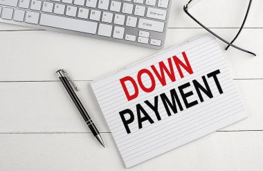 Klavyeli bir not defterinde DOWN PAYMENT metin, beyaz ahşap zemin üzerinde kalem gözlüğü