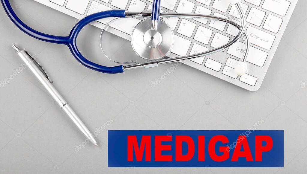 MEDIGAP word with Stethoscope on a keyboard on grey background