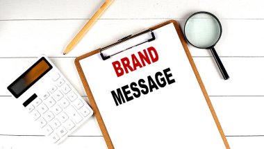 Panoda beyaz tahta zemin üzerinde hesap makinesi, büyüteç ve kalem ile Brand MESSAGE sözcükleri