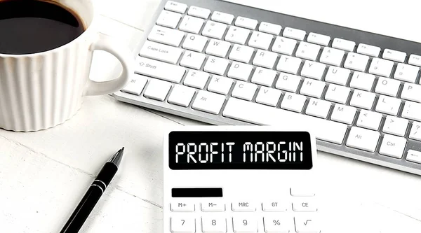 PROFIT MARGIN text on a calculator with keyboard and coffee