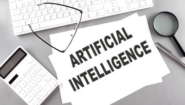Gri arkaplan üzerinde hesap makinesi, klavye ile kağıt üzerinde ARTIFİKA INTELLIGENCE metin
