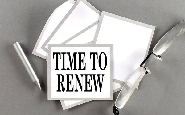 TIME TO RENEW text written on sticky with pencil and glasses