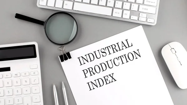 INDUSTRIAL PRODUCTION INDEX written on paper with office tools and keyboard on grey background