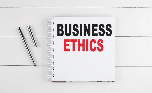 BUSINESS ETHICS text written on a notebook on the wooden background