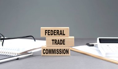 FTC - FEDERAL TRAD KOMİSYONU Not defteri, çizelgesi ve hesap makinesi ile ahşap bir blok üzerinde metin, gri arkaplan
