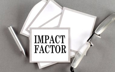 Yapışkan üzerine kalem ve gözlük ile yazılmış IMPACT FACTOR metni
