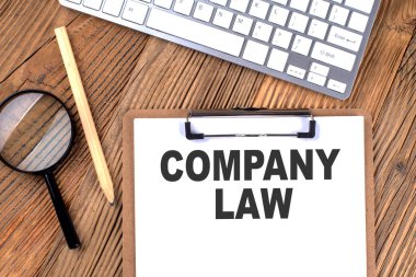 Kağıt pano üzerinde ahşap bir zemin üzerinde büyüteç ve klavye ile COMPANY LAW metin