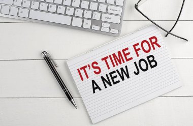 Yeni bir iş metninin zamanı geldi. Klavyeli bir defter, beyaz tahta arka planda kalem gözlüğü.