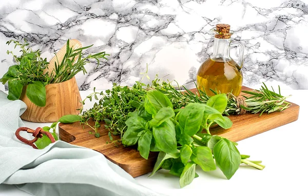 Mix of fresh herbs rosemary, thyme, basil with wooden mortar, napkin and oil. . White background. Top view. Copy space