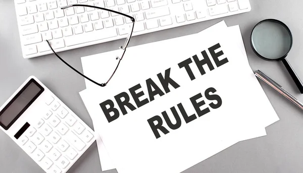 BREAK THE RULES text on a paper with keyboard, calculator on grey background