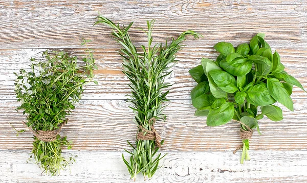 Bunches of thyme, basil and rosemary on a wooden background