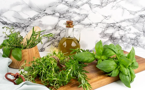 Mix of fresh herbs rosemary, thyme, basil with wooden mortar, napkin and oil. . White background. Top view. Copy space