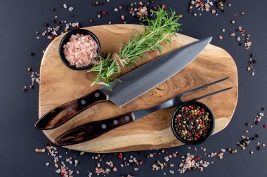 Ahşap kesim tahtası, biberiye ve çatal ve bıçak oymalı baharatlar.