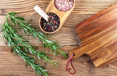Ahşap zemin üzerinde ahşap tahtası olan taze biberiye ve baharat.