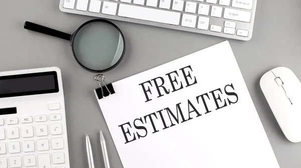 FREE ESTIMATES written on paper with office tools and keyboard on grey background