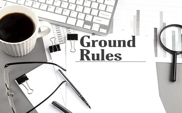 GROUND RULES text on a paper with magnifier, coffee and keyboard on a grey background