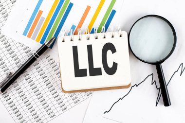 LLC Sınırlı Sorumluluk Şirketi metin grafik arkaplan üzerinde bir defter kalem ve büyüteç ile