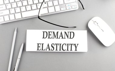 Gri arkaplan üzerinde klavyesi olan bir kağıt üzerinde DEMAND ELASTICITY metni
