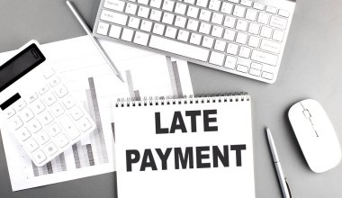 Gri arkaplanda, grafikli ve klavyeli bir not defterine geç ödeme metni, iş konsepti