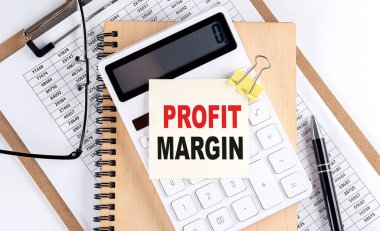Not defteri ve not defteri olan bir yapışkan üzerinde PROFIT MARGIN kelimesi, iş konsepti