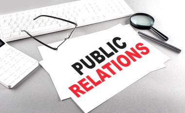 Kağıt üzerinde Klavye ve gri arkaplan üzerinde hesap makinesi ile PUBLIC İlişkileri