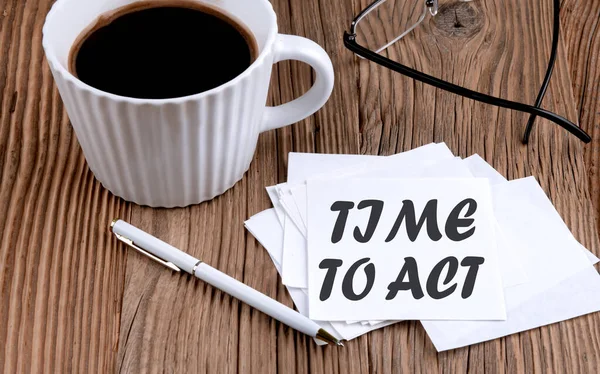 TIME TO ACT text on a sticky with coffee and pen on wooden background