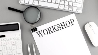 Ofis araçları ve gri arkaplanda klavye ile kağıda yazılan Workshop