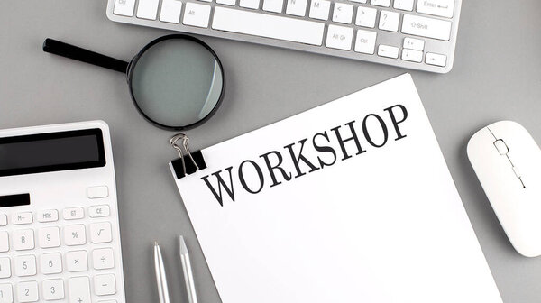 WORKSHOP written on paper with office tools and keyboard on grey background