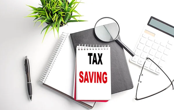 Text TAX SAVING on a notebook with office tools on white background